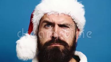 一个戴着一顶<strong>新年帽</strong>子的留着胡子的男人的特写，在蓝色背景下引起了人们的眉毛。 <strong>新年</strong>`概念。 圣诞老人把他